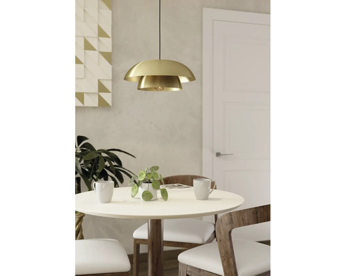 Goudkleurige hanglamp boven een eettafel met stoelen