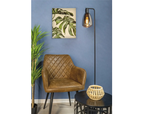 Woonkamer met bruine fauteuil, vloerlamp, tafel en schilderij