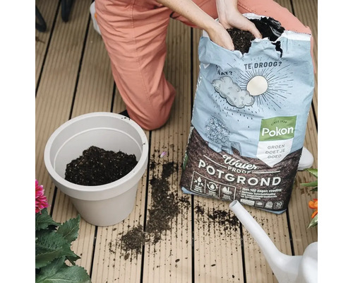 Een persoon vult potgrond uit een Pokon zak in een bloempot.