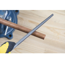 Koperen buis in bankschroef met metalen vijl