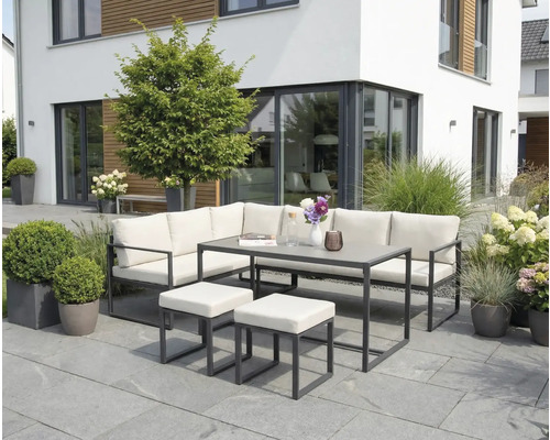 Tuinmeubelset met hoekbank, tafel en krukken op een terras voor een modern huis