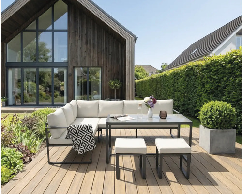 Tuinmeubelset met tafel en krukken op een houten terras voor een huis