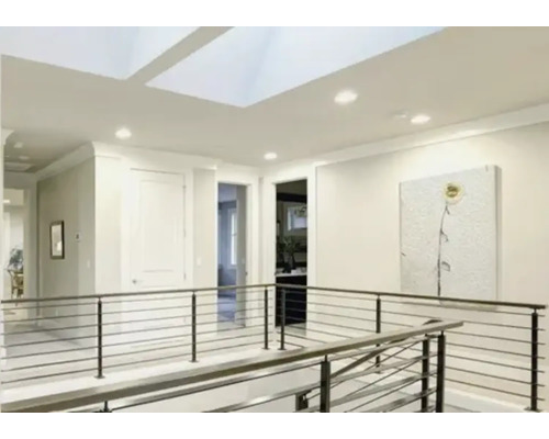 Lichte, moderne overloop met dakramen, inbouwspots en een metalen balustrade met horizontale kabels.