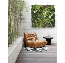 Scène met een fauteuil, een tafel, een rond tapijt en een groen wandpaneel op een terras