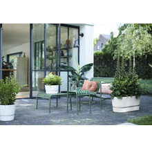 Modern terras met groene metalen tuinbank, bijzettafels en witte bloempotten voor een glazen pui.