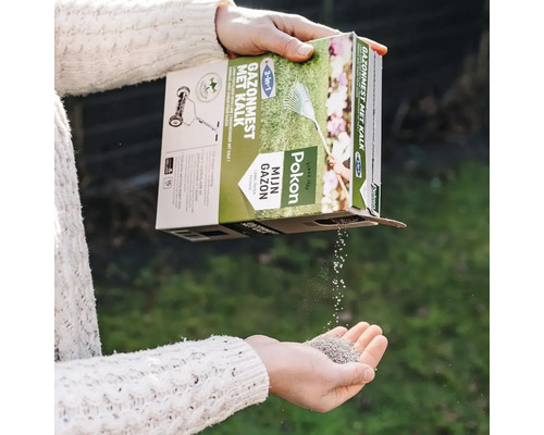 Pokon 3 in 1 gazonmest met kalk wordt vanuit de verpakking in een hand gegoten.