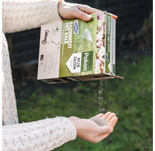 Pokon 3 in 1 gazonmest met kalk wordt vanuit de verpakking in een hand gegoten.