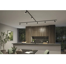 Moderne keuken met zwart railsysteem, kasten in houtlook, een donker kookeiland en eethoek in een lichte, georganiseerde ruimte.