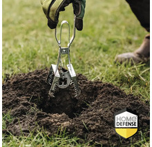 Een hand met tuinhandschoen plaatst een metalen mollenvanger in een molshoop op een gazon. Home Defense Logo.