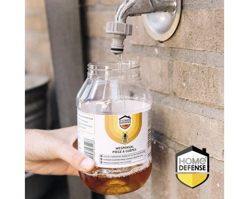Een Home Defense wespenval wordt gevuld met water uit een buitenkraan. Home Defense Logo.