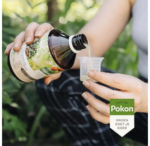 Een persoon schenkt Pokon Bio plantenvoeding uit een fles in een maatbeker. Pokon Logo.