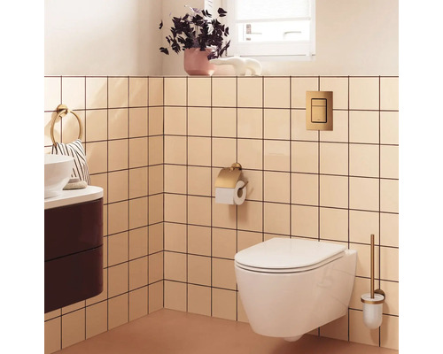 Moderne badkamer met wit hangend toilet, goudkleurige toiletrolhouder, bedieningsplaat en toiletborstel voor vierkante tegels.