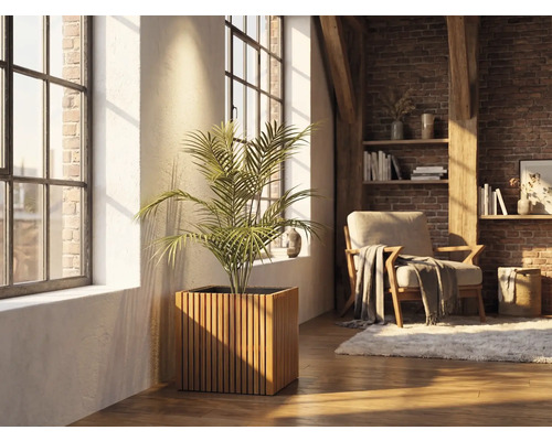 Vierkante houten plantenbak met verticale latten en een kamerplant in een lichte woonkamer met bakstenen muur en grote ramen.
