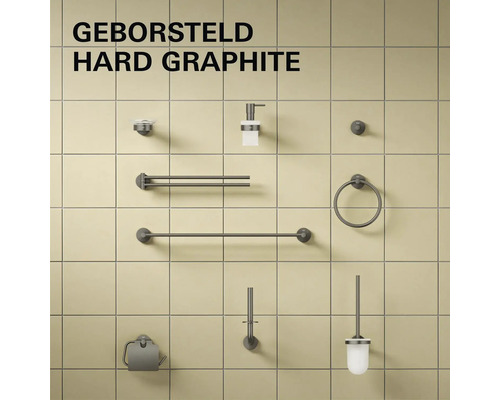 Badkameraccessoireset in geborsteld hard graphite met handdoekhouders, zeepdispenser, toiletborstel en toiletrolhouder op een tegelwand.