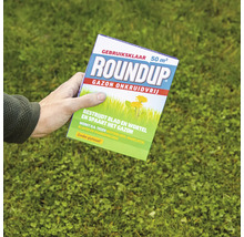 Een persoon houdt een verpakking Roundup Gazon Onkruidvrij onkruidverdelger voor 50 vierkante meter boven een grasveld vast.