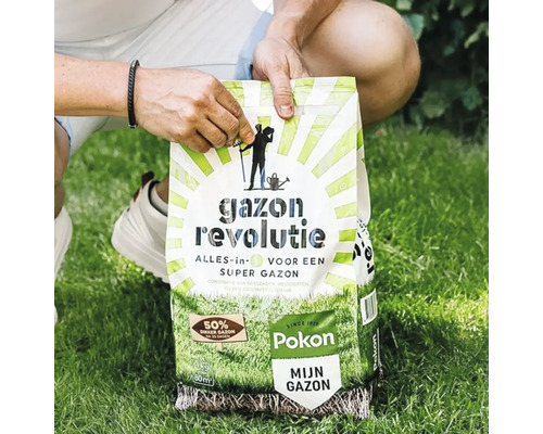 Een persoon houdt een zak Pokon Gazon Revolutie alles-in-één vast op een groen gazon.