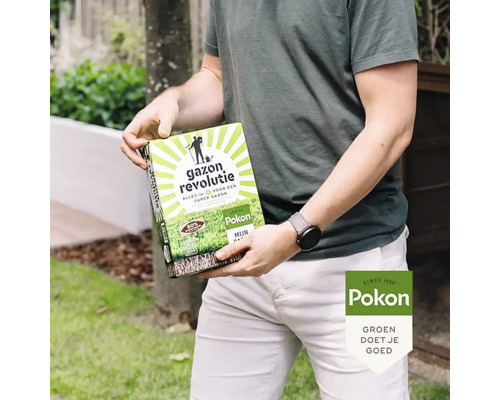 Een persoon houdt een verpakking Pokon Gazon Revolutie graszaad vast in een tuin.