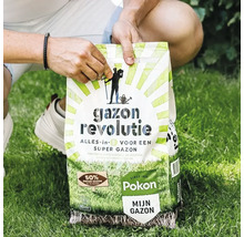 Een persoon houdt een zak Pokon Gazon Revolutie alles-in-één vast op een groen gazon.