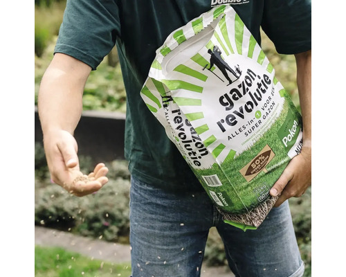 Een persoon zaait handmatig graszaad uit een zak Pokon Gazon Revolutie.