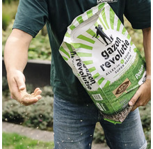 Een persoon zaait handmatig graszaad uit een zak Pokon Gazon Revolutie.