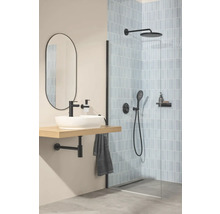 Moderne badkamer met inloopdouche, lichtblauwe tegels, zwarte kranen, witte opzetwastafel op houten plank en een ovale spiegel.
