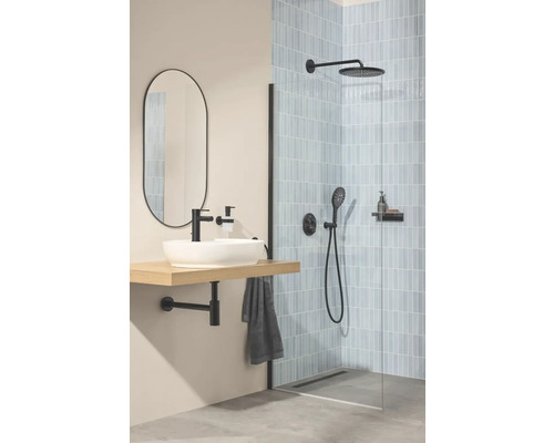 Moderne badkamer met inloopdouche, lichtblauwe tegels, zwarte kranen, witte opzetwastafel op houten plank en een ovale spiegel.