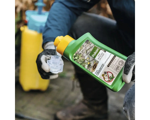 Een persoon met werkhandschoenen giet Pokon onkruidverdelger concentraat uit een groene fles in een maatbeker, met een gele drukspuit op de achtergrond.