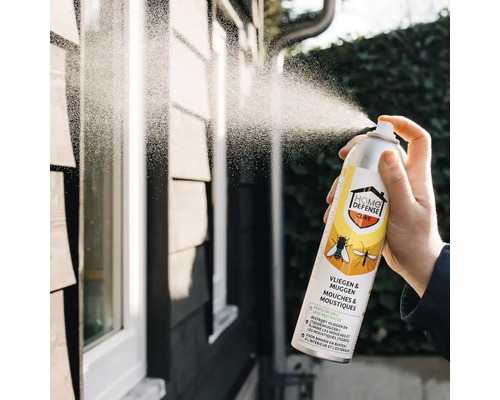 Hand spuit Home Defense Cure insectenspray tegen vliegen en muggen op een buitenmuur.