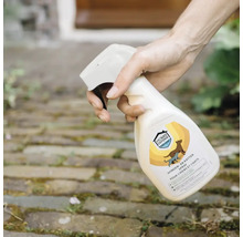 Een hand spuit Home Defense Prevent honden- en kattenspray op een bestraat oppervlak buiten.