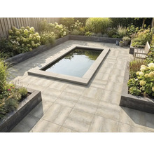 Georganiseerde tuin met een terras van grijze tegels, een centrale rechthoekige vijver en verhoogde borders met hortensia's.