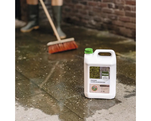 Pokon Groene Aanslagreiniger can op natte terrastegels, op de achtergrond wordt geveegd met een bezem.