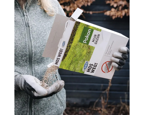 Persoon giet Pokon Mos Weg 2 in 1 mosbestrijder en gazonmest uit de verpakking in een gehandschoende hand voor gazononderhoud.