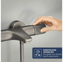 Hand bedient de getextureerde greep van een antracietkleurige badkraan voor het instellen van de waterhoeveelheid en omschakelen tussen bad en douche.