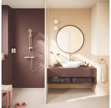 Moderne badkamer met inloopdouche, donkerpaarse tegels, goudkleurig douchesysteem, wastafelmeubel met opzetwaskom en een ronde spiegel.