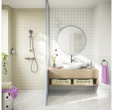 Lichte badkamer met inloopdouche, houten wastafelmeubel, witte opzetwastafel, ronde spiegel en terrazzovloer in een modern ontwerp.