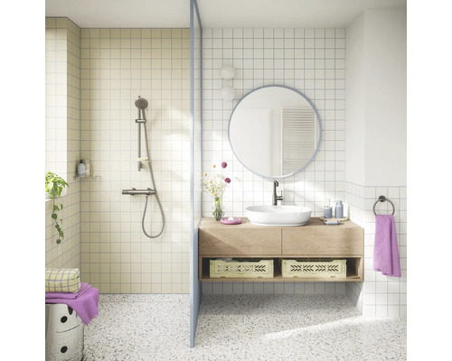 Lichte badkamer met inloopdouche, houten wastafelmeubel, witte opzetwastafel, ronde spiegel en terrazzovloer in een modern ontwerp.