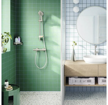 Moderne lichte badkamer met groene douche en metalen doucheset. Blauwe tegels, houten meubel, witte opzetwastafel, ronde spiegel en terrazzovloer.