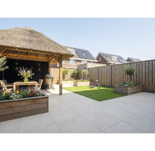 Moderne tuin met terrastegels, houten prieel met rieten dak, houten plantenbakken, klein gazon en houten schutting.