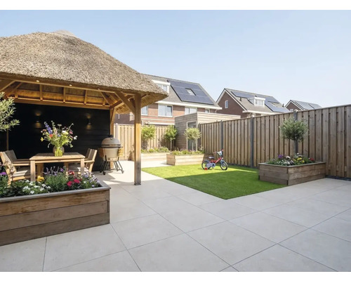Moderne tuin met terrastegels, houten prieel met rieten dak, houten plantenbakken, klein gazon en houten schutting.