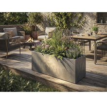 Grote rechthoekige plantenbak met betonlook op een houten terras in een modern ingerichte tuin met zithoek en vuurschaal.