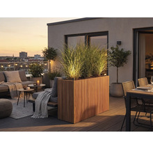 Modern dakterras met verlichte houten plantenbak, hoge grassen, loungemeubels en eethoek bij zonsondergang.
