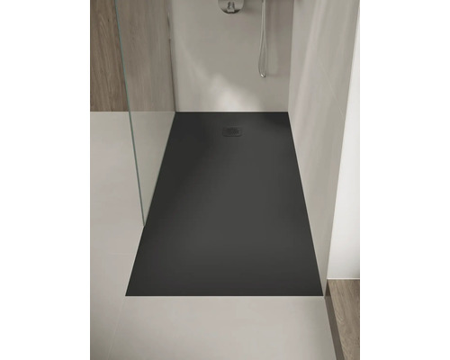 Gelijkvloerse, rechthoekige douchebak in antraciet met een vierkant rooster, geïnstalleerd in een moderne douche met glaswand.