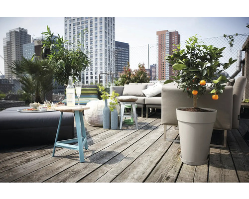 Dakterras met houten vlonder, grijze loungeset, plantenbak met citrusboom, blauwe bijzettafel en uitzicht op de stad.