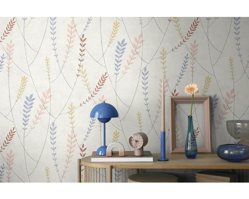 Behang met een patroon van takken en gekleurde bladeren achter een consoletafel met een lamp, vaas en decoratieve voorwerpen.
