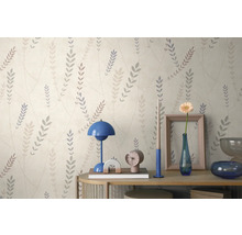 Vliesbehang met fijn bladpatroon op een lichte achtergrond boven een dressoir met tafellamp en decoratie.