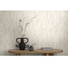 Behang met een bladpatroon achter een houten consoletafel met vaas en decoratieve voorwerpen in een modern interieur.