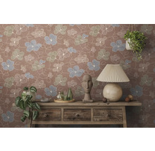 Vliesbehang met bloemenpatroon op een muur achter een houten dressoir met tafellamp, buste en kamerplanten.