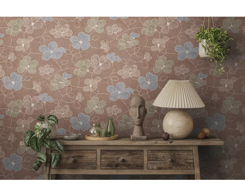 Vliesbehang met bloemenpatroon op een muur achter een houten dressoir met tafellamp, buste en kamerplanten.