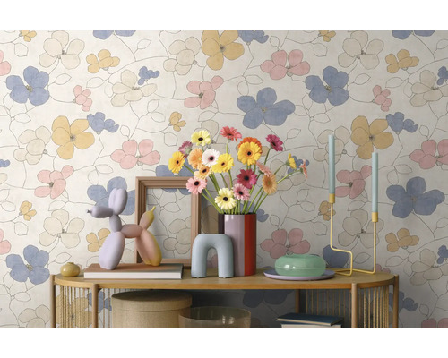 Vliesbehang met een groot bloemenpatroon in pasteltinten op een muur achter een gedecoreerde console.