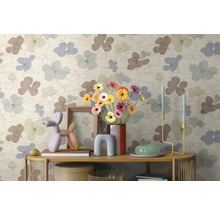 Vliesbehang met groot bloemmotief in lichte kleuren, gecombineerd met moderne decoratie op een sidetable.